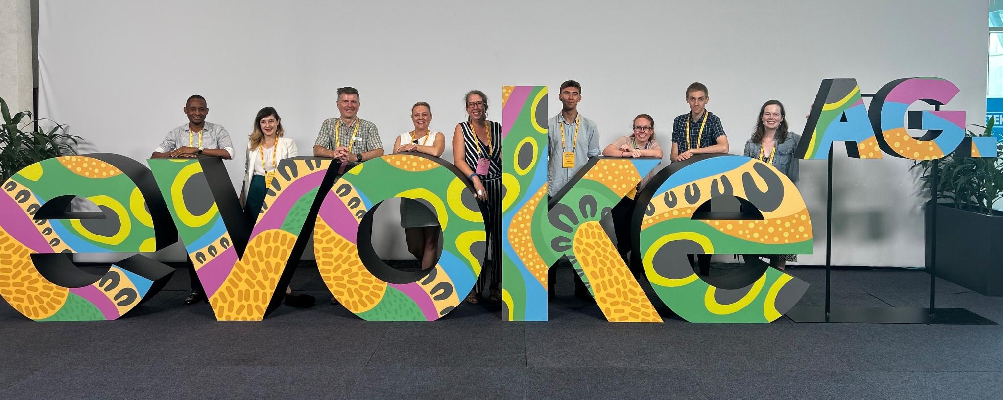 A colourful sculpture of the word 'evoke', people standing behind it.